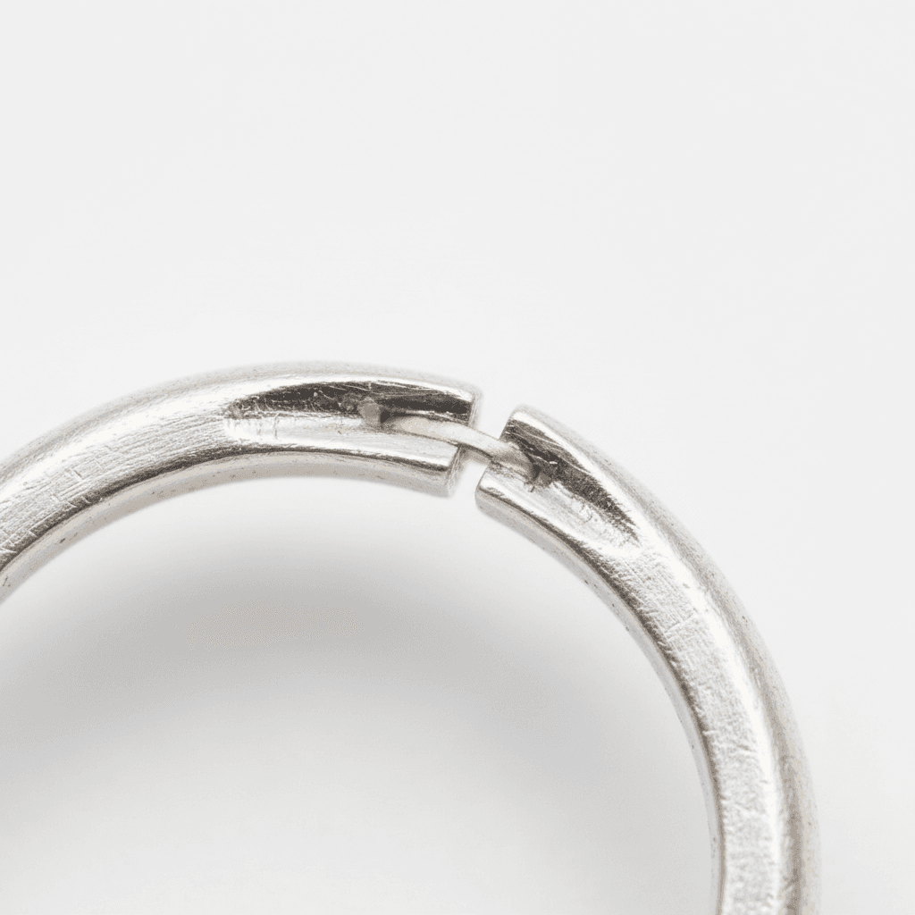 Close-up of a brushed silver open-band ring with a small gold accent at the gap