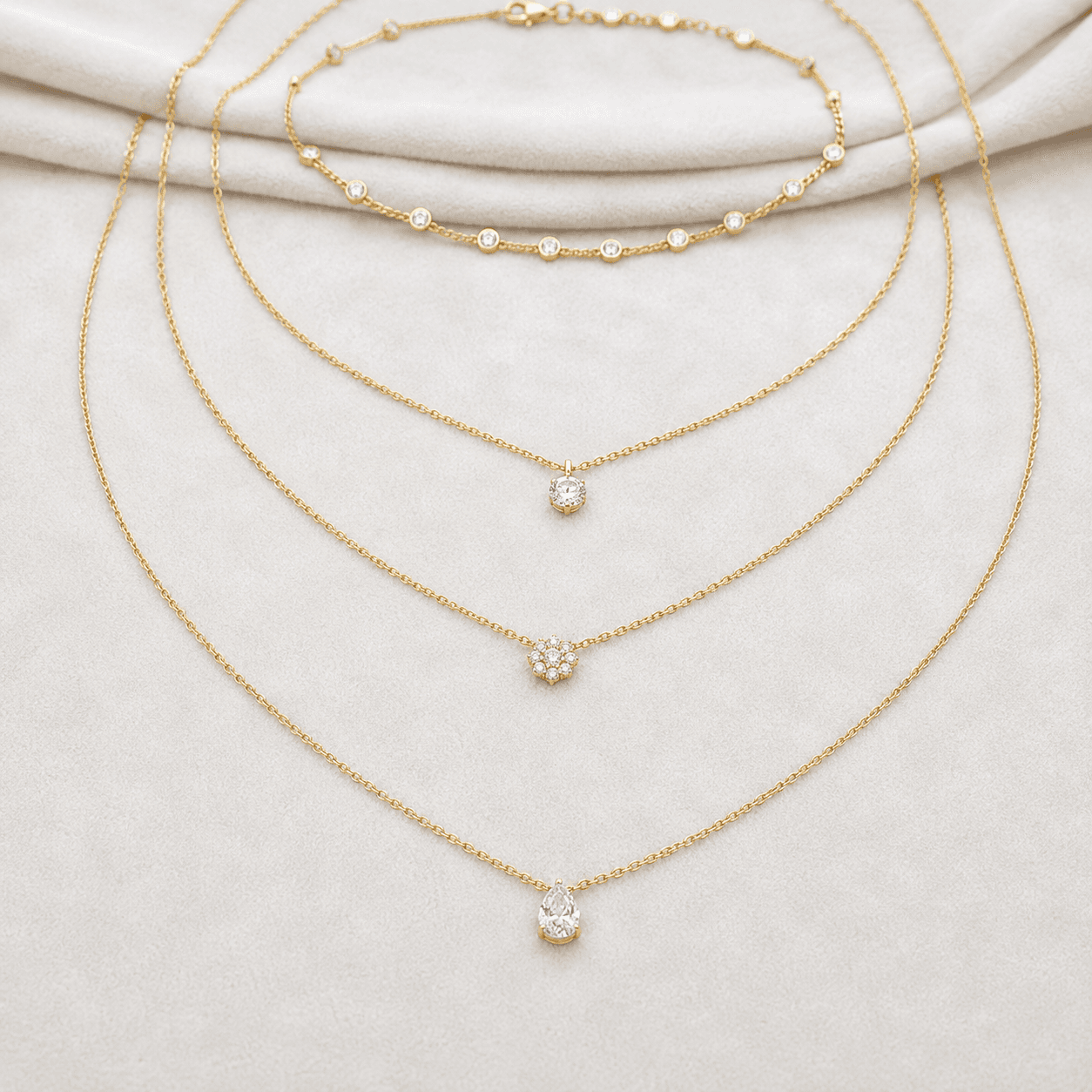 An array of necklaces in different lengths laid flat on white velvet, choker, princess, matinee, photographed from above